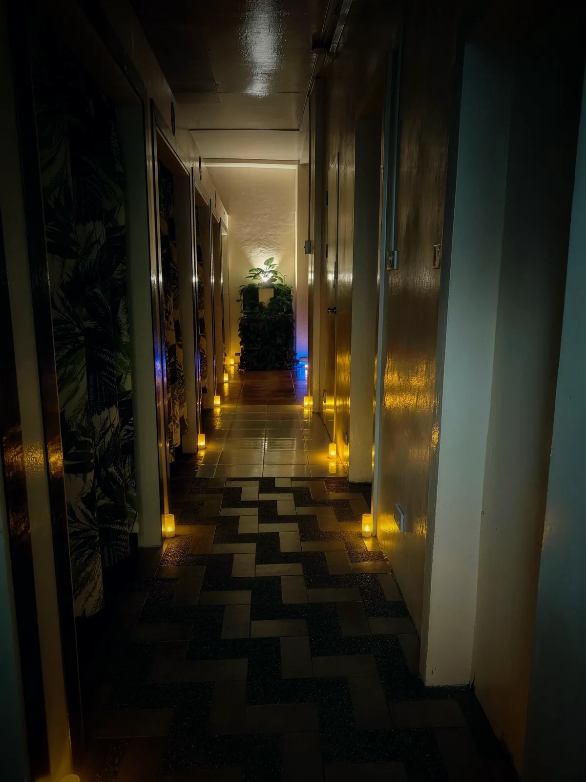 The candle-lit corridor at Dipolog Massage — warm candles lining a zigzag-tiled hallway, with private curtained rooms to the side