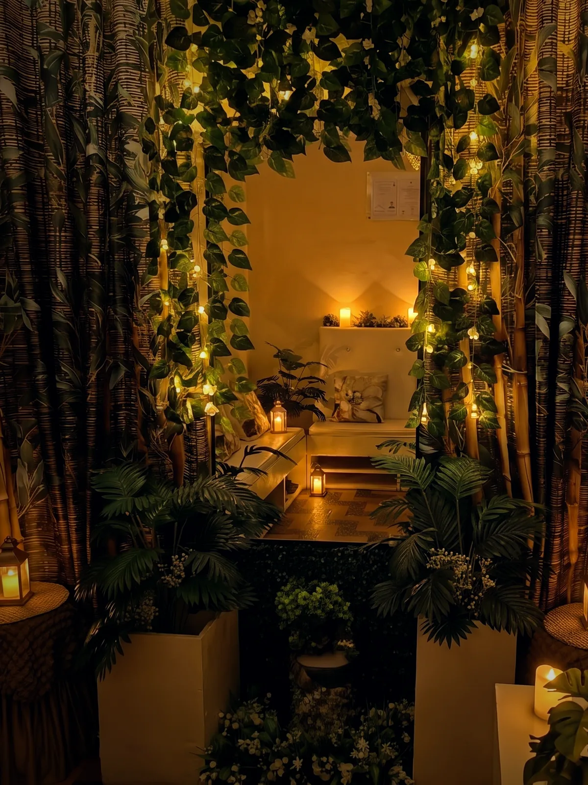 The Dipolog Massage reception nook — a white bench framed by an archway of greenery, warm with candlelight